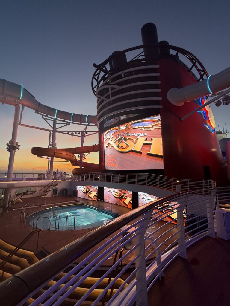 Funnel Vision screen and family pool aboard the Disney Wish at sunset